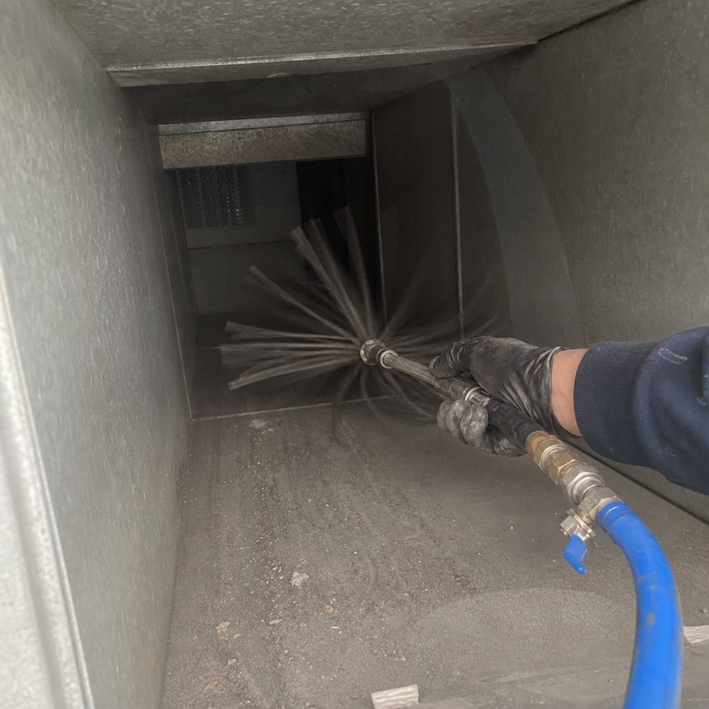 Professional air duct cleaning with brush tool and blue hose